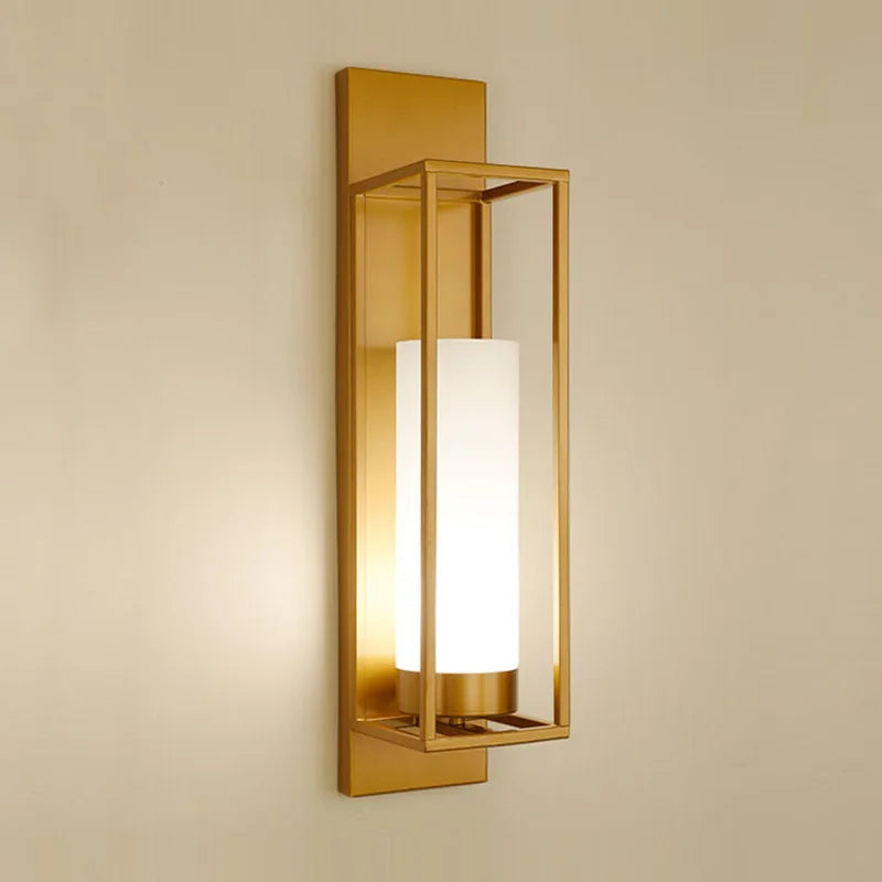 Gold wall sconce with a white glass shade on a beige wall