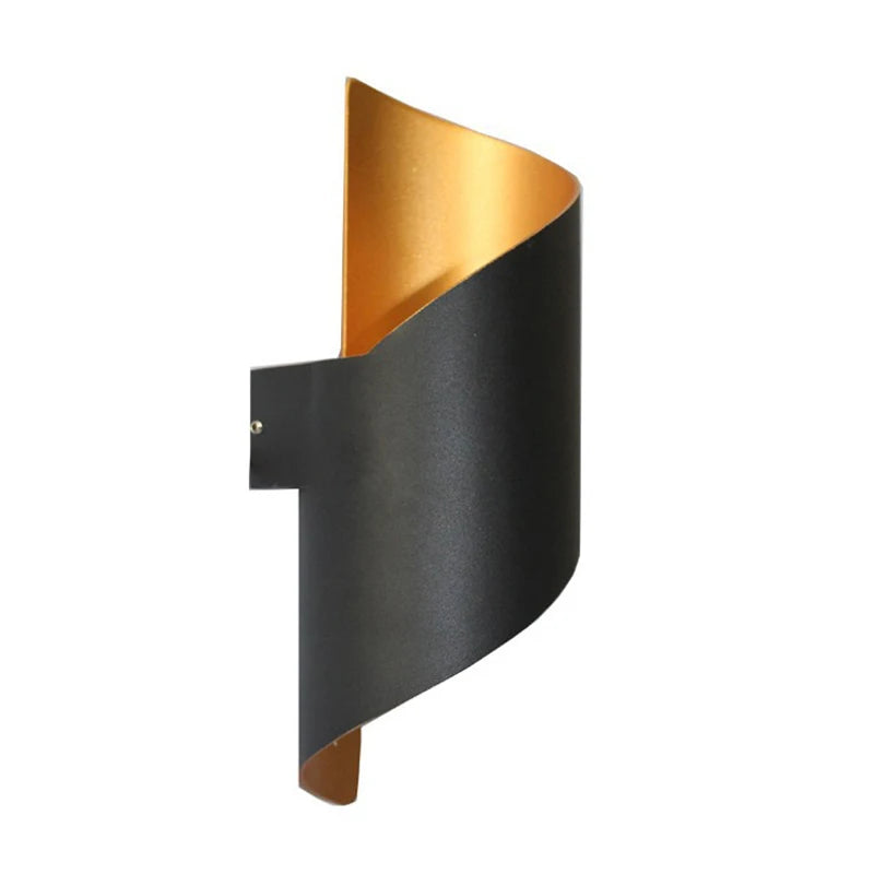 “Black curved aluminium wall light glowing with gold interior reflector.”