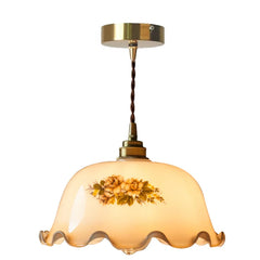 Decorative pendant light with floral design on a white background. American brass glass pendant light with a floral cream shade for retro kitchens.
