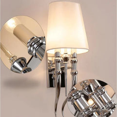Chrome wall sconce with a white lampshade on a neutral background