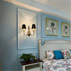 Decorative wall sconce with floral wall art in a bedroom setting.