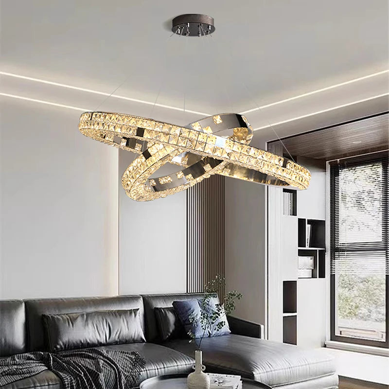 Modern chandelier hanging above a living room with a sofa and bookshelf.