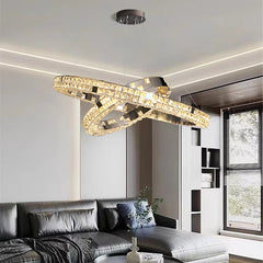 Modern chandelier hanging above a living room with a sofa and bookshelf.