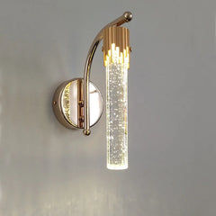 Gold wall sconce with a cylindrical glass shade on a gray background