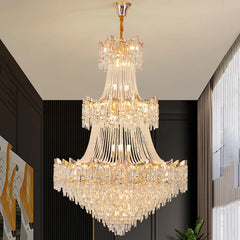 Luxurious crystal chandelier hanging in a room with dark walls and a plant.