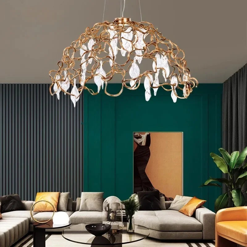 Gold chandelier hanging in a living room with a green wall and gray sofa.