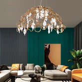 Gold chandelier hanging in a living room with a green wall and gray sofa.