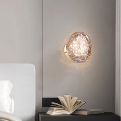 Decorative wall light fixture on a neutral wall with an open book on a surface below.