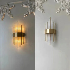 Two gold wall sconces on a decorative white wall.