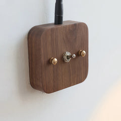 Wooden wall switch with brass knobs on a white wall