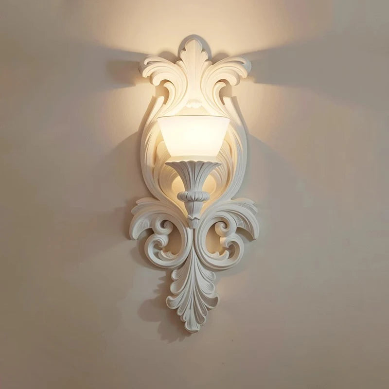 Decorative wall sconce with intricate design on a plain wall.