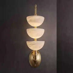 Wall-mounted light fixture with three tiered glass shades on a dark background