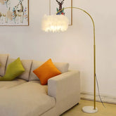 Gold feather arc floor lamp for living room or sofa corner beige sofa, orange pillow, green pillow, and a gold floor lamp.