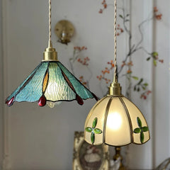 Two stained glass pendant lights with floral designs on a decorative wall background. Handcrafted stained glass bedside pendant with LED support.