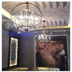 Two crystal chandeliers hang from the ceiling with a lion painting in the background. Handcrafted iron cage vintage chandelier with crystal accents.