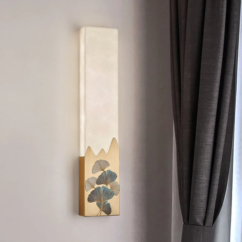 Decorative wall sconce with leaf design on a neutral wall next to a gray curtain.