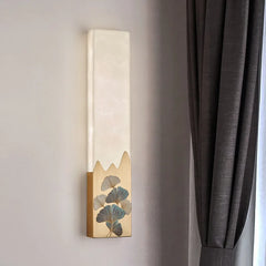 Decorative wall sconce with leaf design on a neutral wall next to a gray curtain.