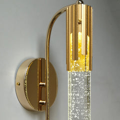 Gold wall sconce with a clear glass shade on a gray background