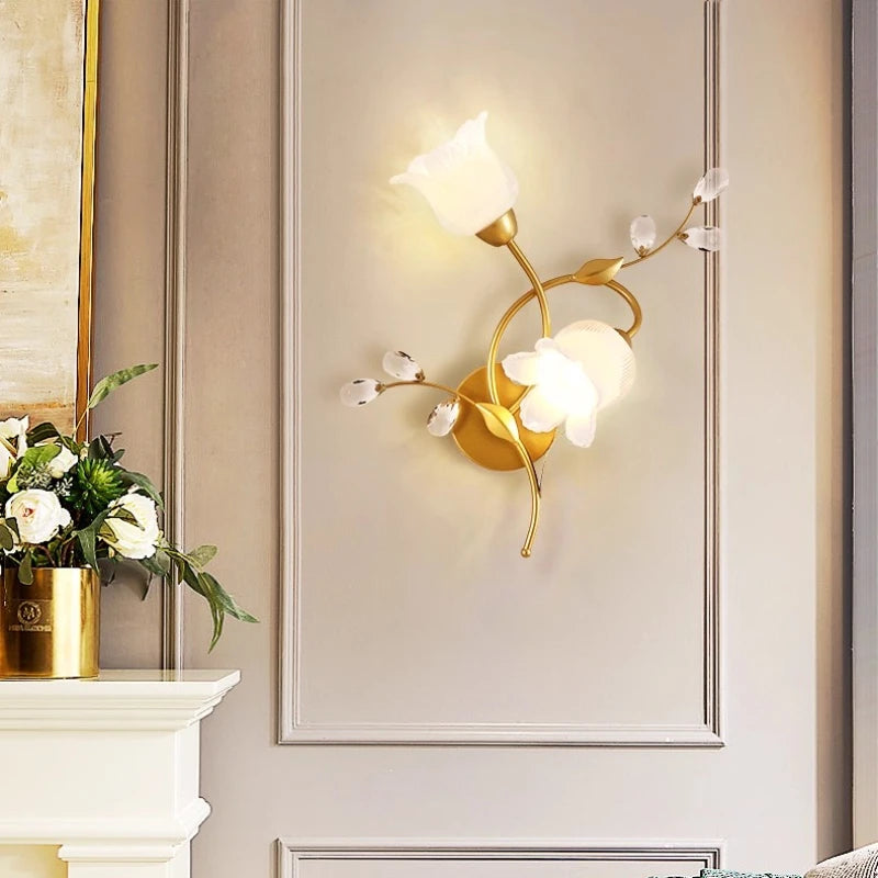 Decorative wall light fixture on a wall with a vase of flowers on a mantelpiece.