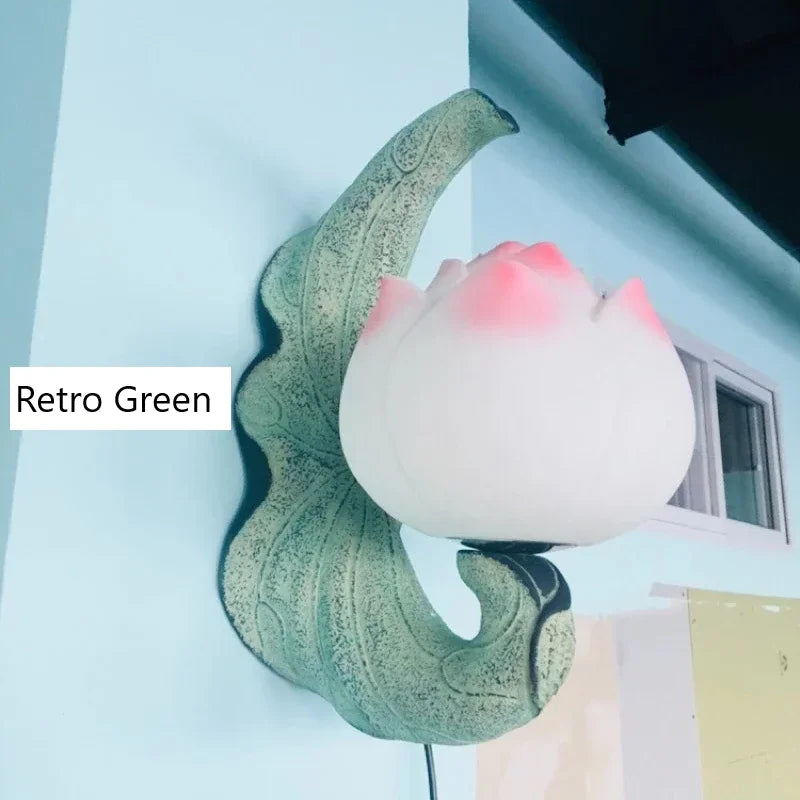 Decorative wall light with retro green base and pink lampshade on a light blue background.