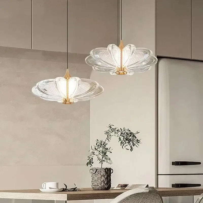 Two modern pendant lights hang above a kitchen counter with a plant and a bowl. Liglite modern minimalist chandelier illuminating bar counters with LED lights