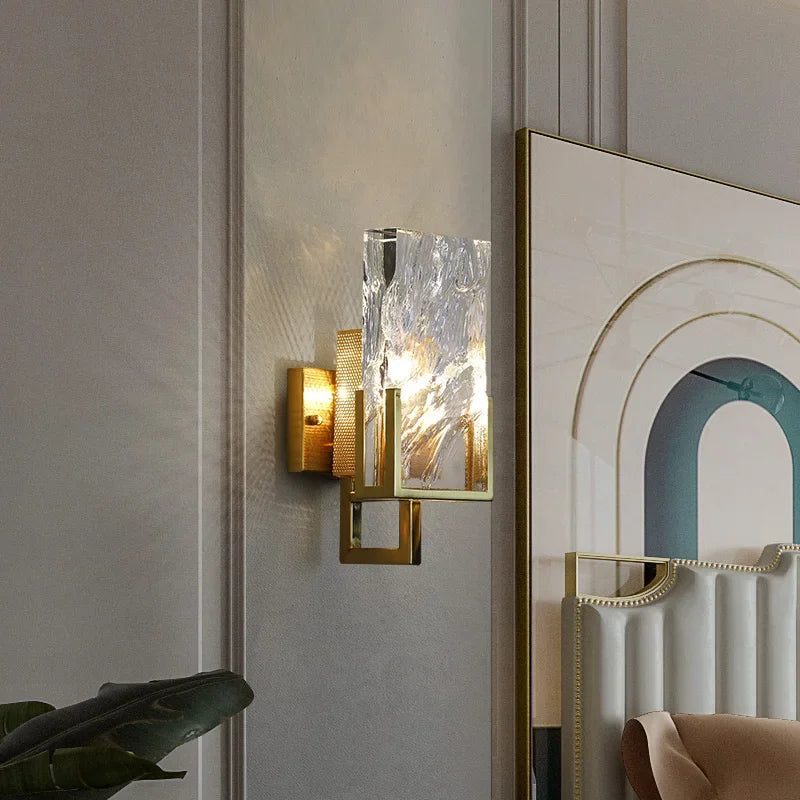 Decorative wall sconce with glass shade on a wall next to a mirror.