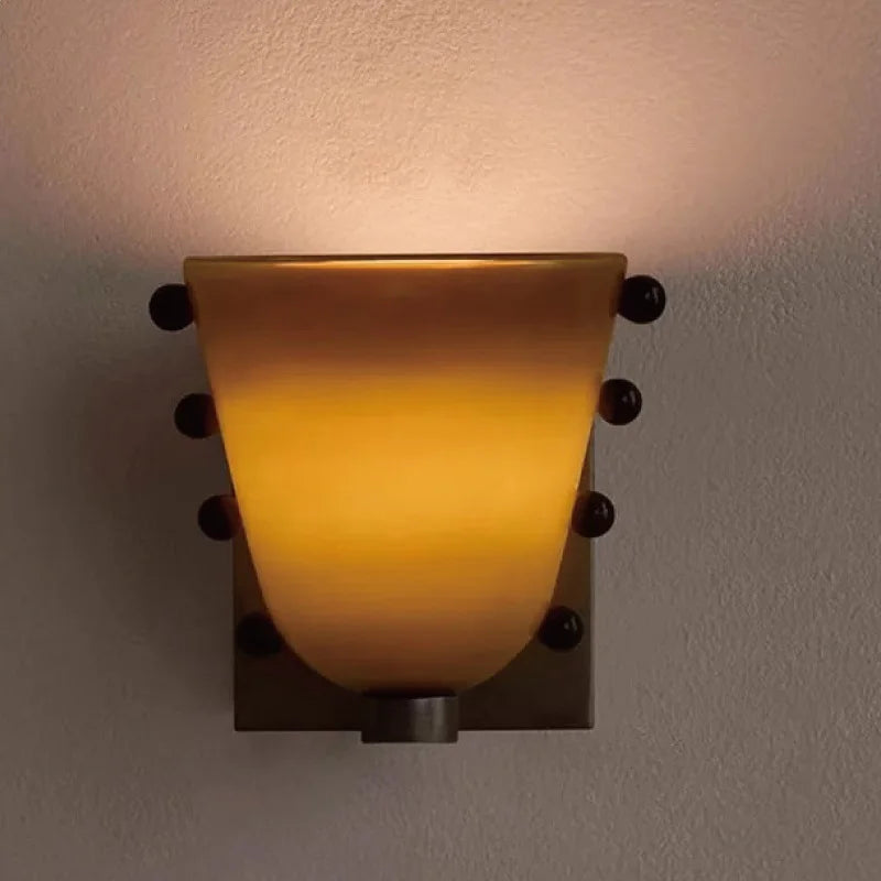 Wall-mounted light fixture with a warm glow on a plain wall