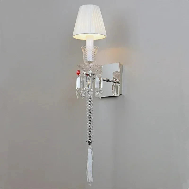 Wall-mounted lamp with crystal details and a white shade on a gray wall.