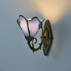 Wall-mounted lamp with butterfly-shaped purple glass shade on a light blue wall.