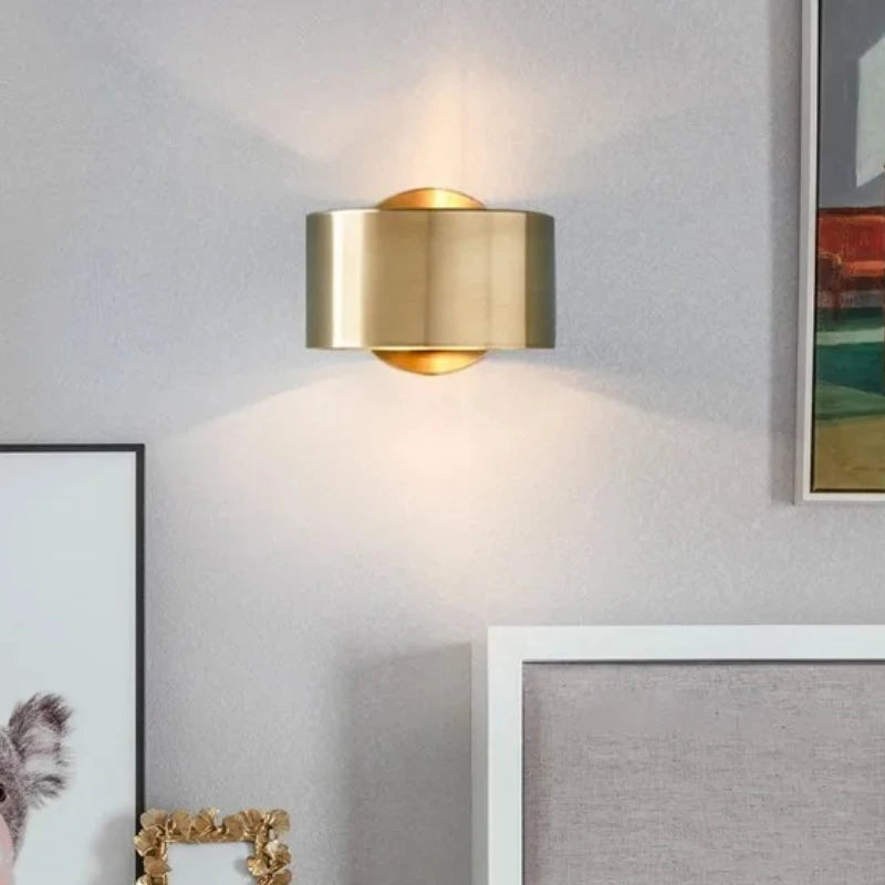Gold wall sconce on a gray wall with framed pictures.