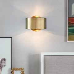 Gold wall sconce on a gray wall with framed pictures.