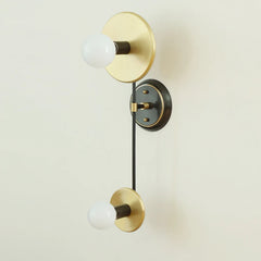 Modern wall sconce with gold and black finish on a light beige background