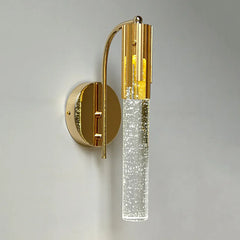 Gold wall sconce with clear glass on a gray background