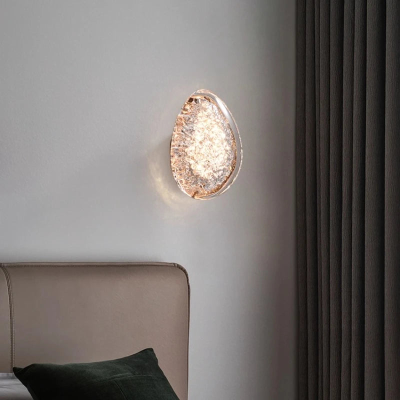 Decorative wall light fixture on a gray wall with a bed and dark curtains in the background.