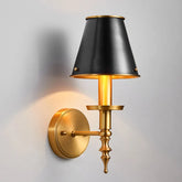 Wall-mounted lamp with black shade and gold base on a gray background