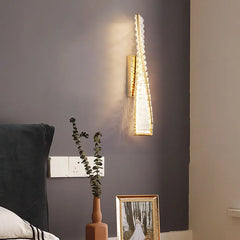 Wall-mounted light fixture on a dark wall with decorative elements below.