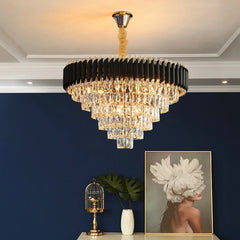 Chandelier hanging in a room with a blue wall, small table with decorative items, and a framed picture.