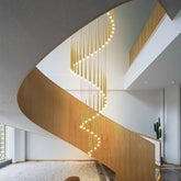Spiral LED chandelier hanging through a modern staircase opening