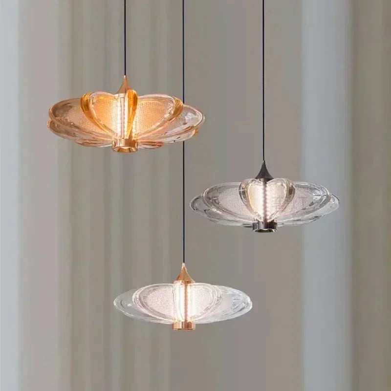 Three modern pendant lights with glass shades on a neutral background; Petal minimalist crystal chandelier with glass shades for a modern bar or restaurant.