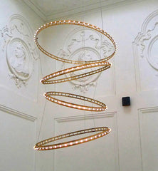 Dramatic spiral metal circle chandelier illuminating a villa staircase lobby