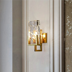 Decorative wall sconce with glass shade on a neutral wall.