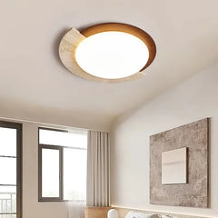 “Travertine and wood flush mount ceiling lamp glowing softly in a modern bedroom.”