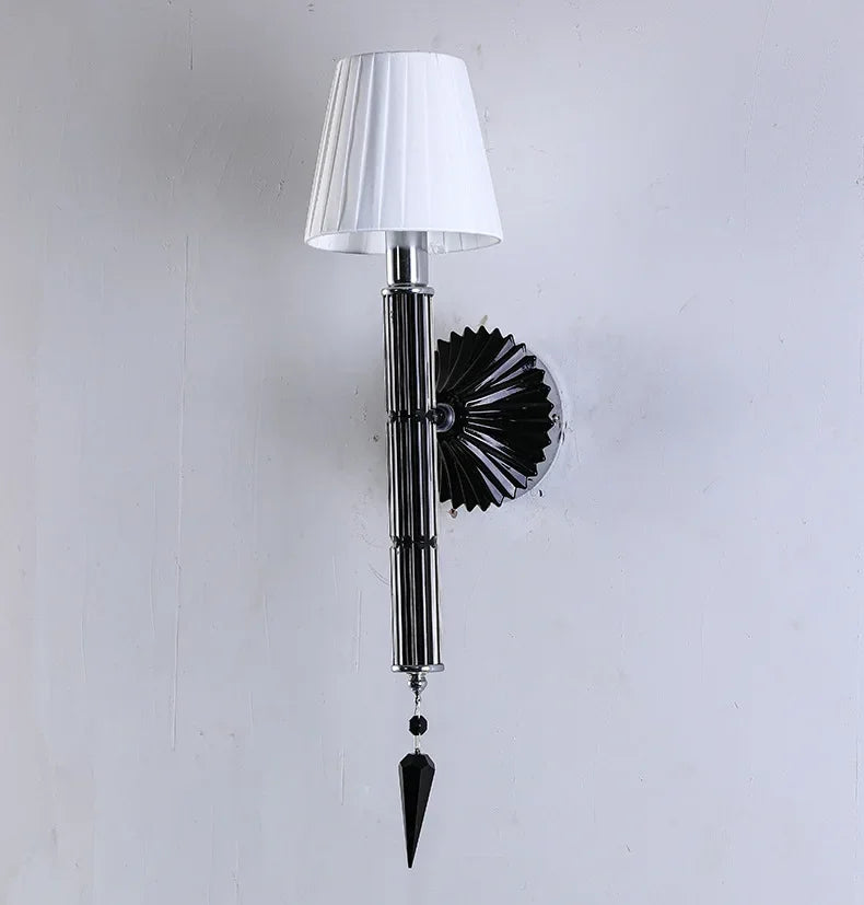 Wall-mounted lamp with a white shade and decorative black base on a light gray background