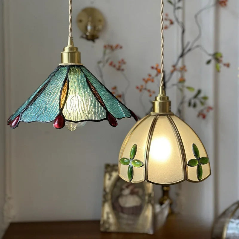 Two stained glass pendant lights with floral designs on a decorative wall background. Vintage stained glass pendant lamp for kitchen or loft lighting.
