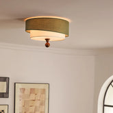 “Green fabric drum ceiling light in a bright room, casting a soft ambient glow.”