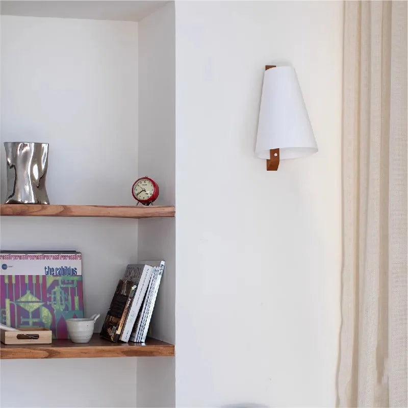 Wall-mounted lamp next to a wooden shelf with books and decor items.