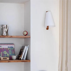 Wall-mounted lamp next to a wooden shelf with books and decor items.