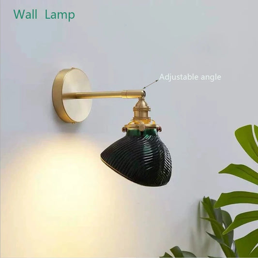 Green fluted glass wall sconce with adjustable brass arm, illuminating a wall
