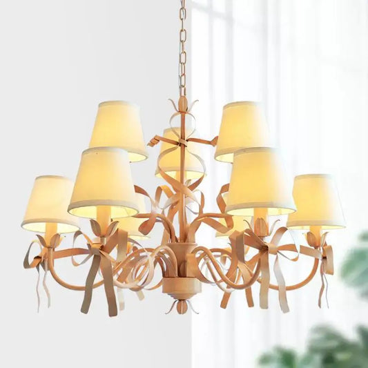 Pink ribbon chandelier with eight fabric shades and decorative bows, mounted from a chain.