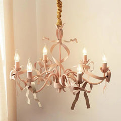 Close-up of a pink chandelier with candle-style bulbs and intricate ribbon detailing.